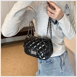Close-up of black quilted leather shoulder bag featuring silver chain and metal turn-lock