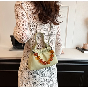 Detail of light green ruched cloud bag with amber bead handle and chain strap