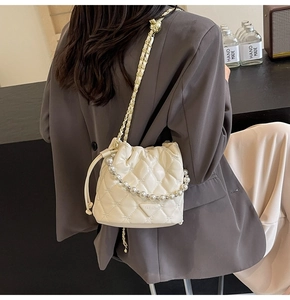 Détail du sac seau matelassé blanc avec bandoulière en perles et chaîne en métal doré