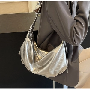 Silver metallic soft leather tote bag with adjustable strap worn by model in side view