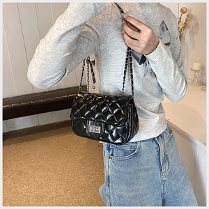 Side view of black quilted crossbody bag featuring chain strap on fashion model