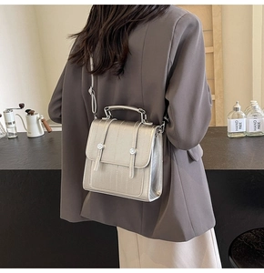 Detail of silver metallic textured crossbody bag shown on model in urban lifestyle setting