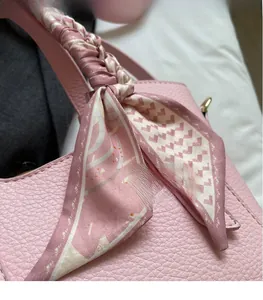 Close-up of pink lychee grain leather handbag with decorative geometric silk scarf knot