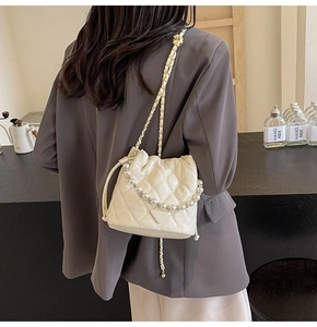 Détail du sac seau matelassé blanc crème avec poignée en perles et bandoulière chaîne