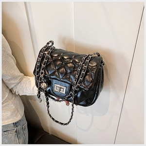 Detail of black quilted leather shoulder bag with silver chain strap and metal turn-lock