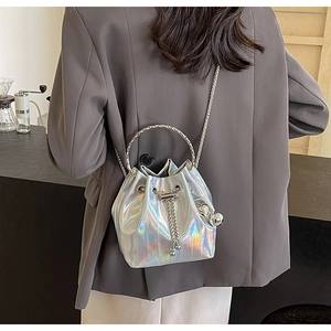 Detail of silver holographic bucket bag with vertical quilting and metal chain strap on model