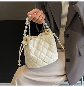 Détail du sac seau matelassé crème avec poignée en perles et fermeture à cordon