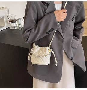 Détail du sac seau matelassé blanc avec poignée en perles et chaîne sur un mannequin