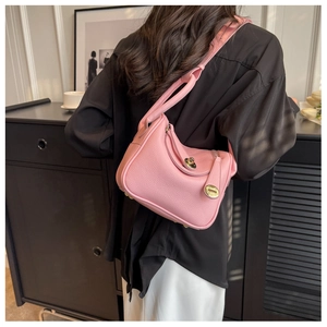 Détail du sac seau en cuir grainé rose avec fermoir rotatif métallique et bandoulière