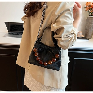 Detail of black PU crossbody bag with unique brown beaded handle and chain strap