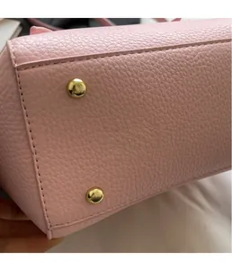 Macro detail of pink pebble leather bag base with golden protective metal feet