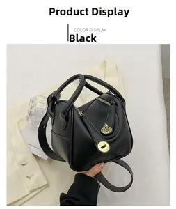 Détail du sac en cuir noir grainé avec fermoir pivotant en métal doré brillant
