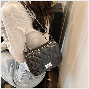 Detail of classic black quilted chain bag with silver twist lock and glossy finish