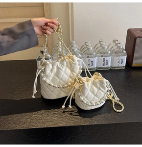 Détail du sac seau matelassé blanc crème avec poignée perle et chaîne dorée