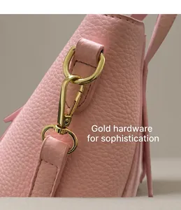 Detail of pink lychee leather handbag with shiny gold metal hook and precise stitching