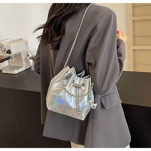 Silver laser bucket bag with chain strap and metal ball detail on a grey blazer