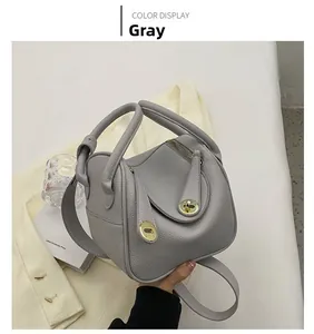 Détail du sac à main en cuir grainé gris avec fermoir rotatif doré et bandoulière réglable