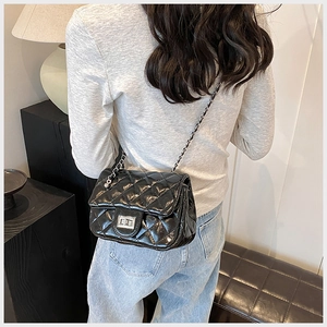 Quilted black patent leather chain bag detail with silver rotary lock and metal strap