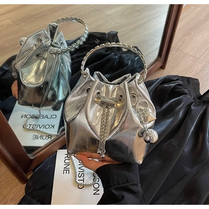 Close-up of silver bucket bag with metallic texture, drawstring closure and heart charm