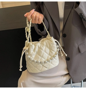 Détail du sac seau matelassé crème avec chaîne en perles et motif de couture en étoile