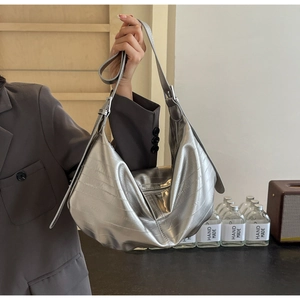 Detail of silver tote bag featuring crocodile pattern texture and adjustable metallic buckle