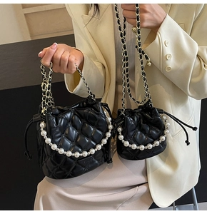 Détail de sacs seaux matelassés noirs avec poignées en perles et chaînes dorées