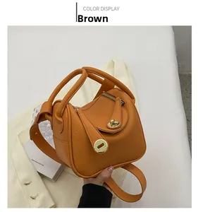 Détail du sac seau en cuir litchi marron avec boucle dorée et poignée enroulée