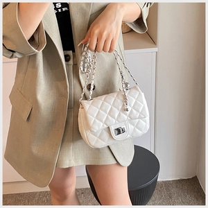 Close-up of white quilted crossbody bag with silver chain strap and metal swivel lock