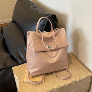 Pink embossed faux leather backpack with metal twist lock and top handle on stone