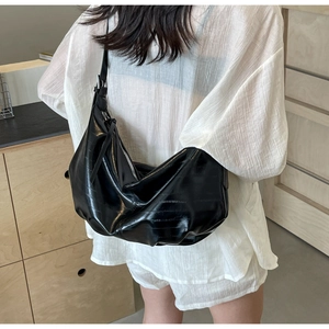Rear view of black hobo bag with horizontal pleated texture on a female model
