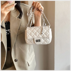 Detail of white quilted crossbody bag with silver twist lock and chain strap