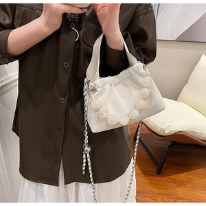 Detailed view of a white cloud-shaped handbag featuring pearl beads and a metal chain strap
