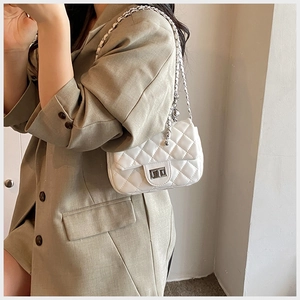 Side view of woman wearing a white quilted chain bag with silver twist lock detail