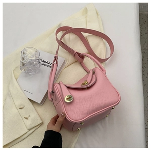 Détail du sac seau en cuir rose avec ferrures dorées et poignée latérale