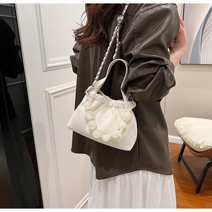 Detail of cream pleated bucket bag with large white bead handle and chain shoulder strap