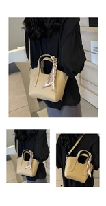 Detail of khaki pebbled leather bucket bag with decorative silk scarf and long strap