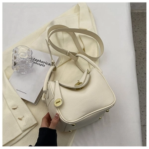 Détail du sac seau en cuir beige grainé avec fermoir rotatif doré élégant