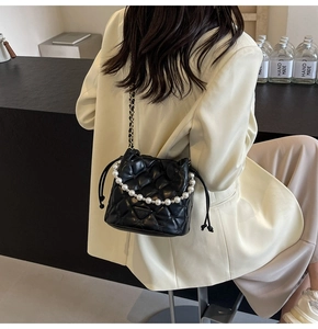 Détail du sac seau noir matelassé avec poignée en perles et bandoulière chaîne
