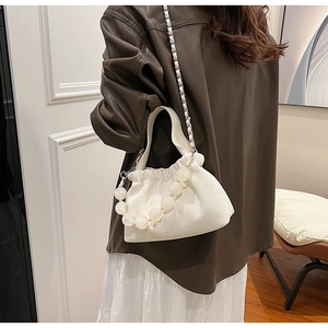 Dettaglio di una borsa a secchiello bianca arricciata con perle opache e catena