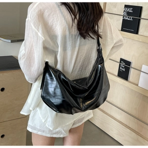 Model view of black glossy moon bag with horizontal texture and wide shoulder strap