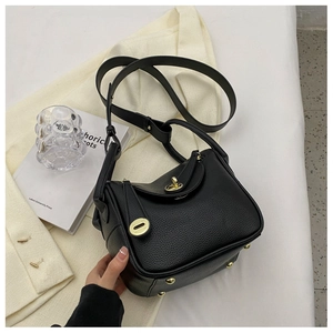 Vue détaillée du cuir noir grainé et du fermoir doré sur le sac à main de style seau