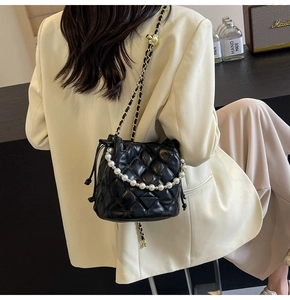 Détail du sac seau noir matelassé avec poignée en perles et bandoulière en chaîne