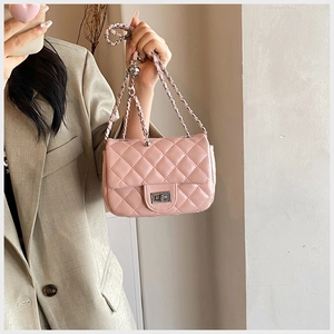 Detail of pink quilted crossbody bag with silver chain strap and metallic twist lock