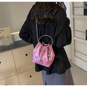 Detail of pink holographic bucket bag with golden ring handle and heart charm