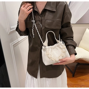Detail view of cream pleated PU leather handbag with decorative pearl handle and chain strap