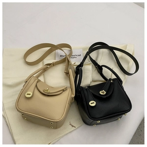 Détail de sacs à main en cuir grainé beige et noir avec fermoirs rotatifs métalliques dorés