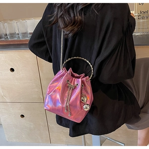 Detail of pink laser bucket bag with metallic handles, chain strap and heart charm
