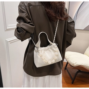 Detail of off-white pleated bucket bag with large acrylic beads and a metal chain strap
