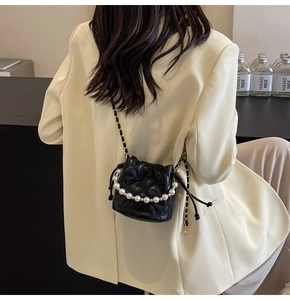 Sac seau noir matelassé avec anse en perles et bandoulière chaîne porté par un mannequin