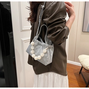 Silver drawstring bucket bag with large faux pearl handle and metal chain strap details